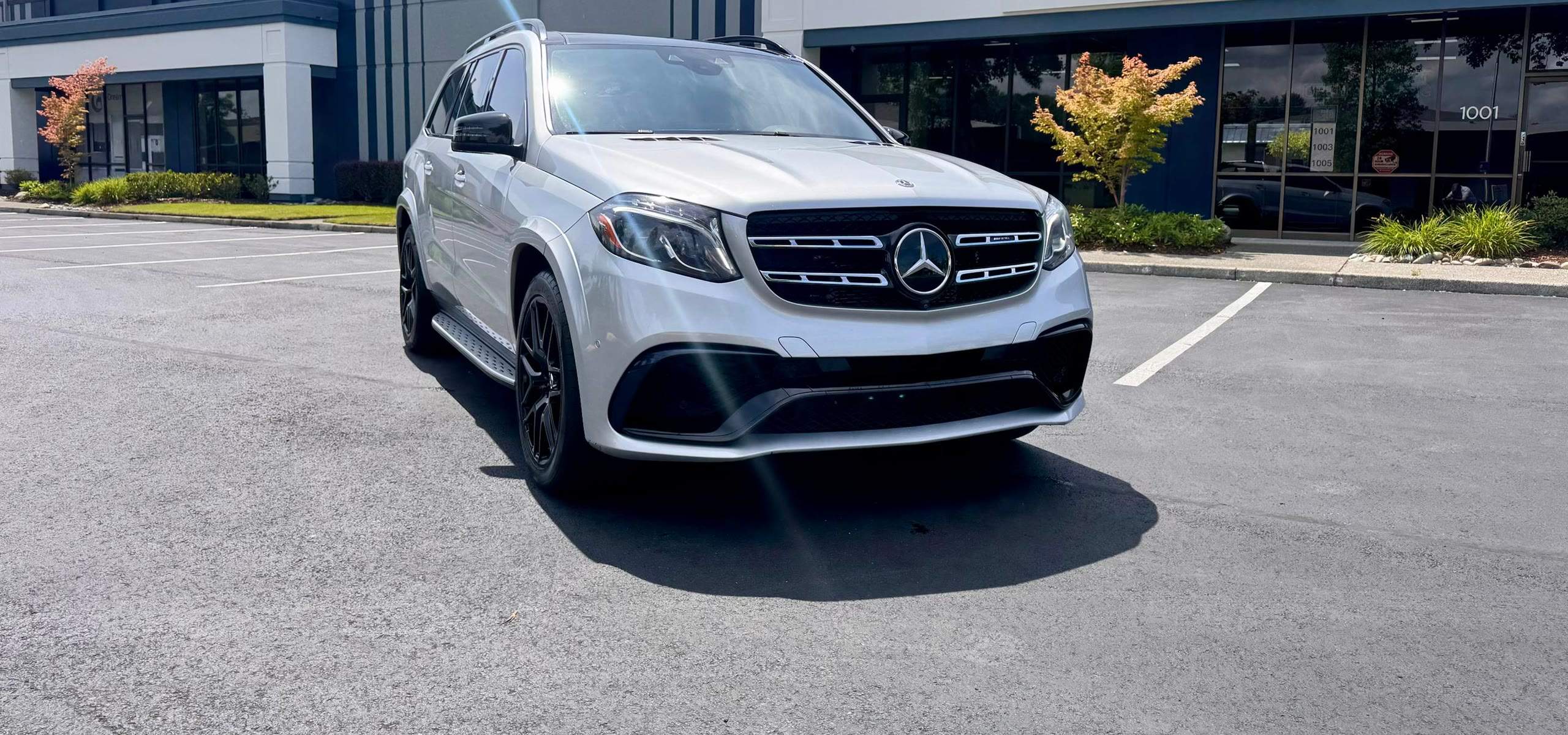 Mercedes-AMG GLS 63 under a sunny blue sky at the Luxcar Rentals facility in Tukwila, Washington
